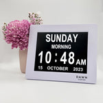 Original Dawn Clock - Calendar and Date Screen on table. The Dawn Clock™ is the original LED calendar day clock that has specially designed on-screen alerts to enable independence in completing daily tasks. The on screen reminder alerts help to alleviate the stress of reminding as well as the frustration of being reminded. With a high contrast and low glare screen, The Dawn Clock™ is easy to read and understand. Plug in and go with an automatic start and a user-friendly interface. ADHD Autism Disability